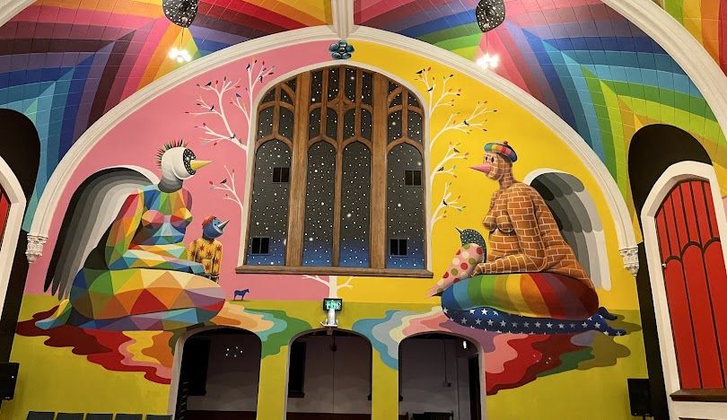 Inside the International Church of Cannabis, vibrant neon murals burst with color, creating a mesmerizing and uplifting atmosphere.