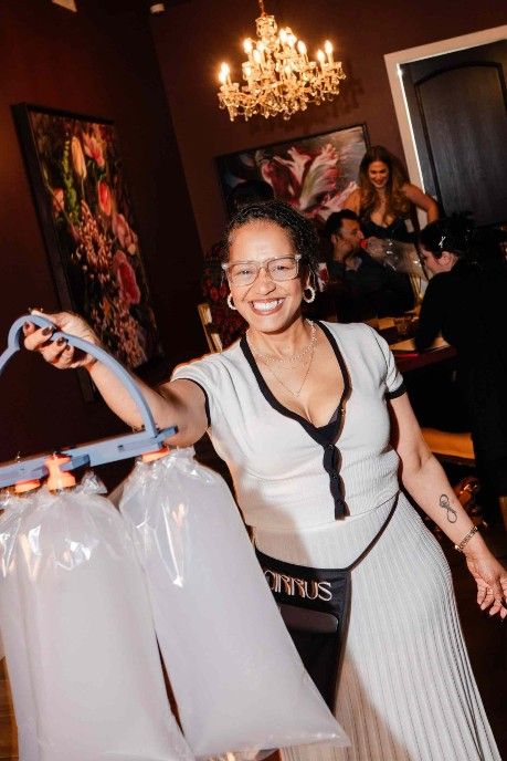 Alt Text: Light-skinned woman holding a smoke-filled weed bag, smiling in a chic lounge setting at Cirrus Social Club, highlighting a luxurious and responsible cannabis experience.